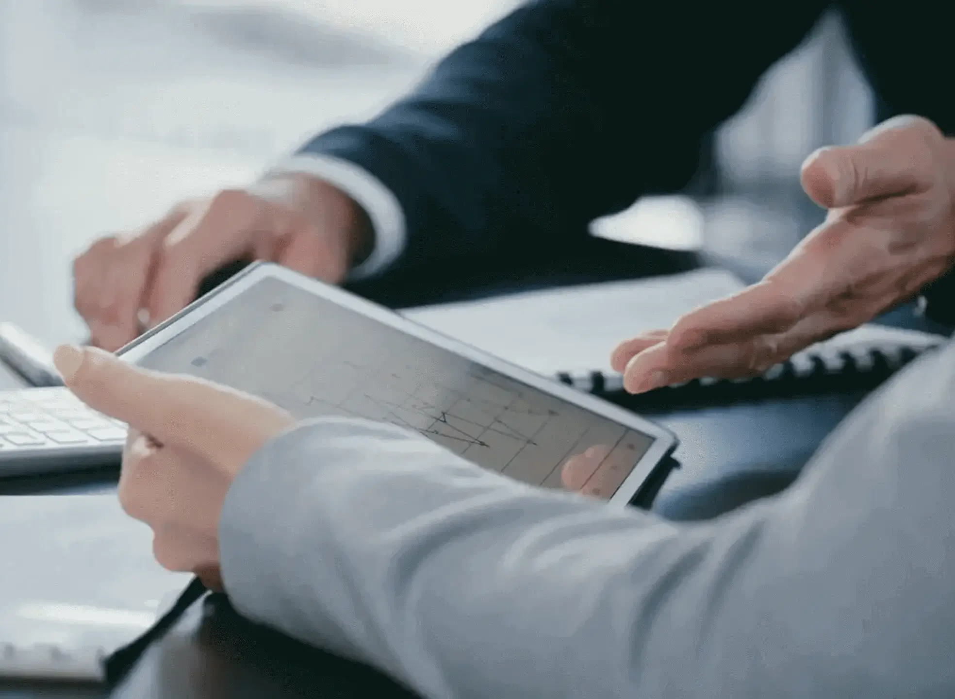 Two people discussing data on a tablet during a business meeting.