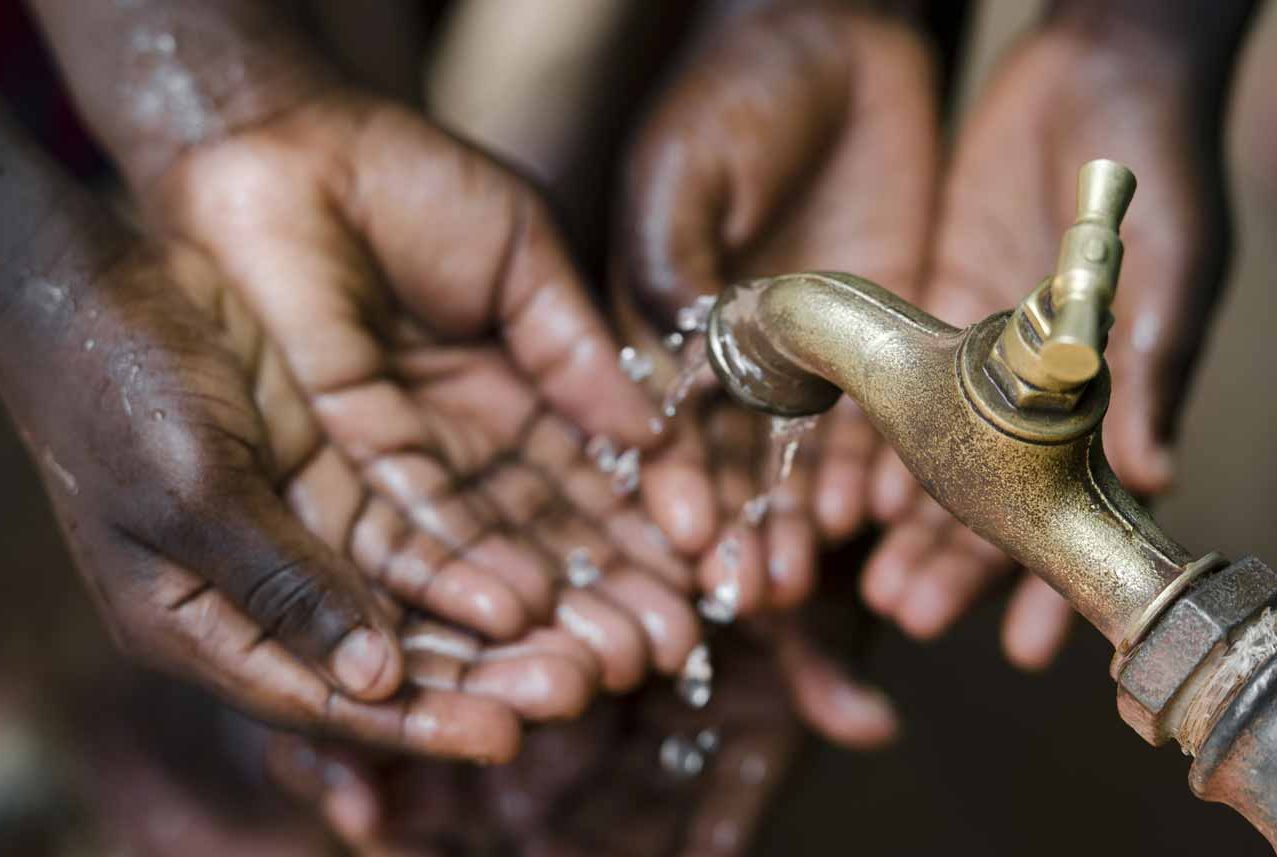 A photograph of hands under a tap of dripping water